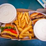 Delicious cheeseburger meal with crinkle-cut fries and drinks, perfect for a quick lunch or fast food craving.